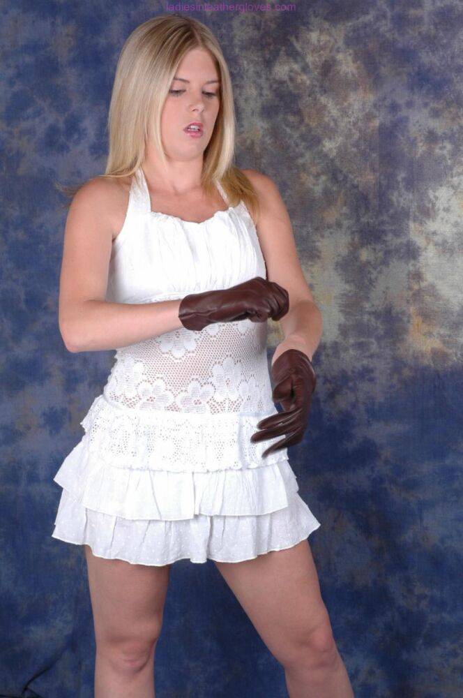 Blonde female pulls on brown leather gloves while wearing a white dress - #14