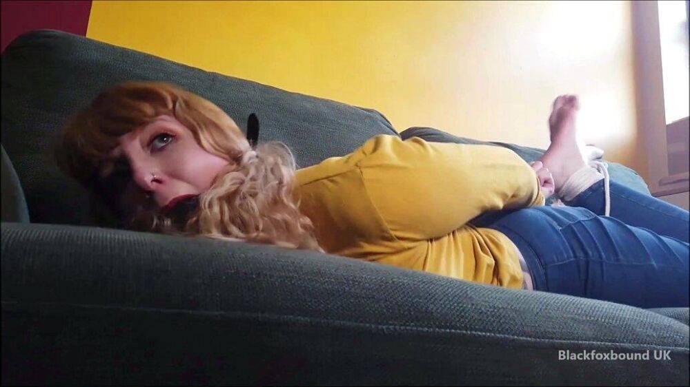 Barefoot white girl is hogtied on a sofa while ball gagged in her clothing - #1