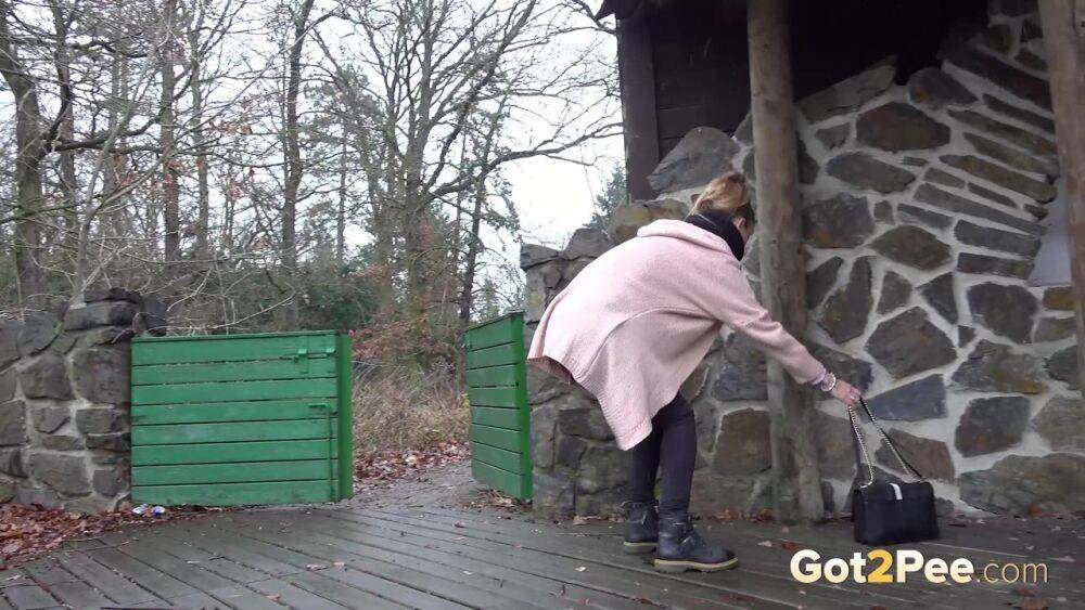 White girl Cynthia Vellons takes a piss on a deck behind a stone structure - #10