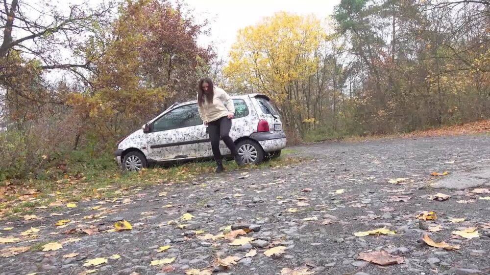 White girl Nicolette Noir takes a piss beside a parked car in a wooded setting - #2