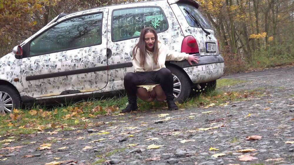 White girl Nicolette Noir takes a piss beside a parked car in a wooded setting - #5