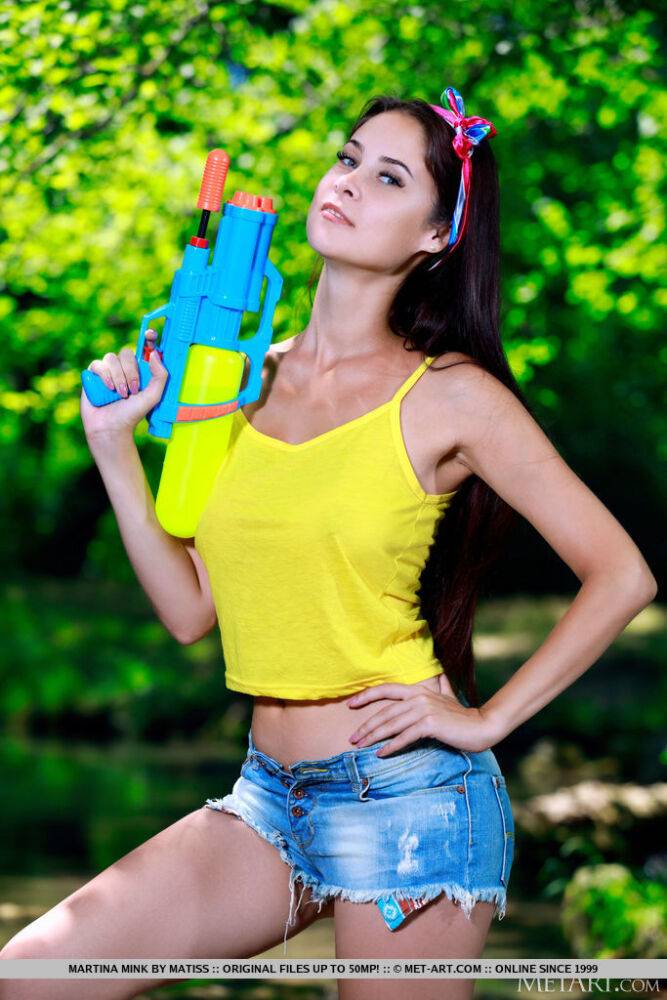 Young brunette Martina Mink wields a water gun while getting naked by a brook - #4