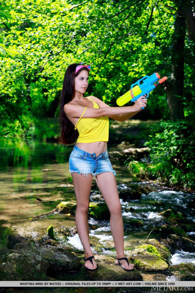 Young brunette Martina Mink wields a water gun while getting naked by a brook - #15