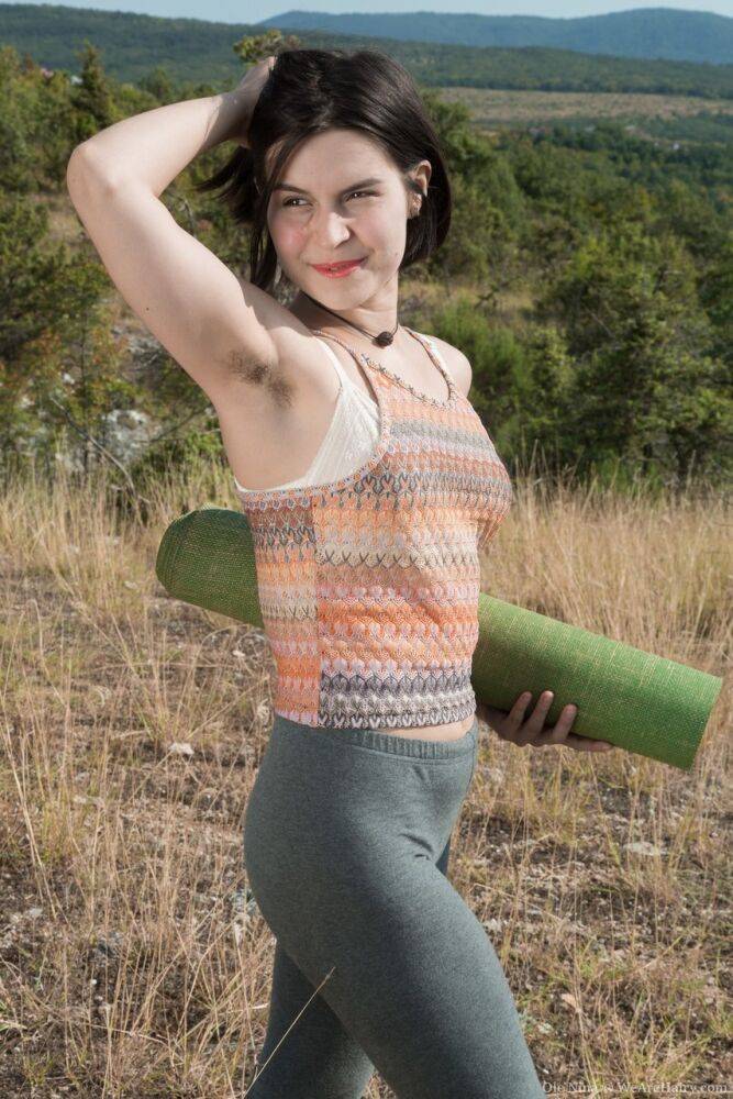 All natural amateur Ole Nina lays on a yoga mat under the clear sky atop hill - #2