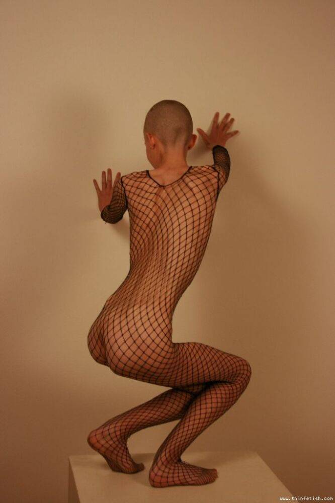 Solo model with a shaved head poses in a fishnet bodystocking - #13