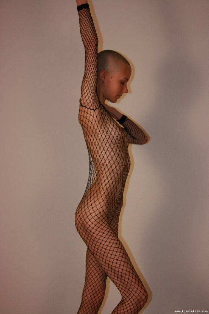 Solo model with a shaved head poses in a fishnet bodystocking - #8