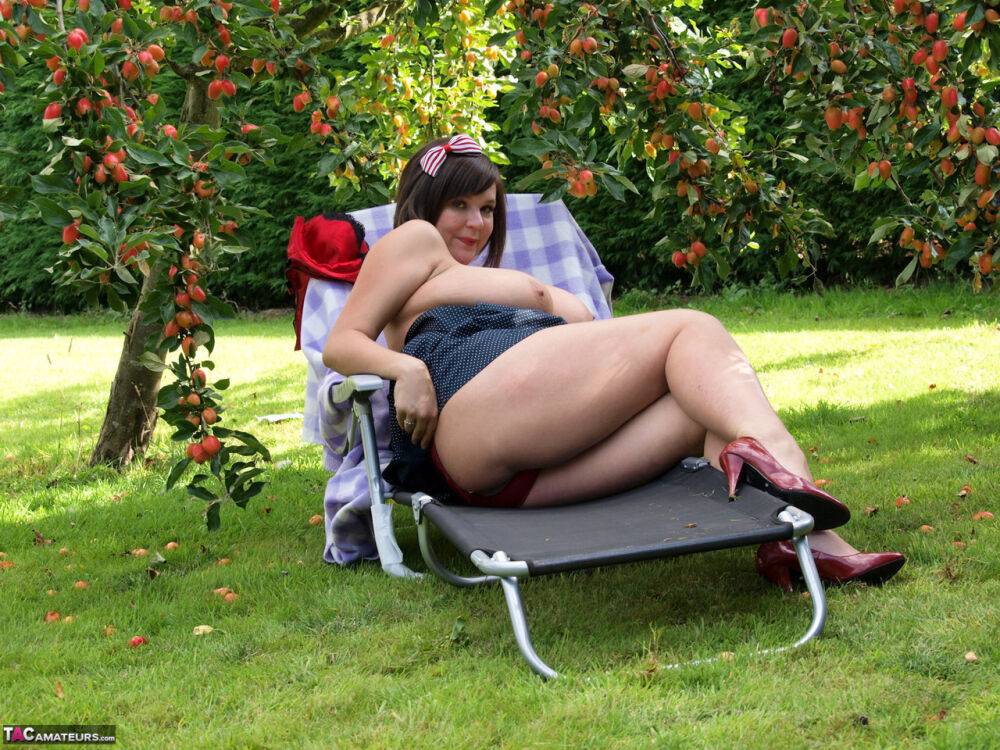 Plump amateur Roxy displays her huge boobs and bald cunt under a fruit tree - #9