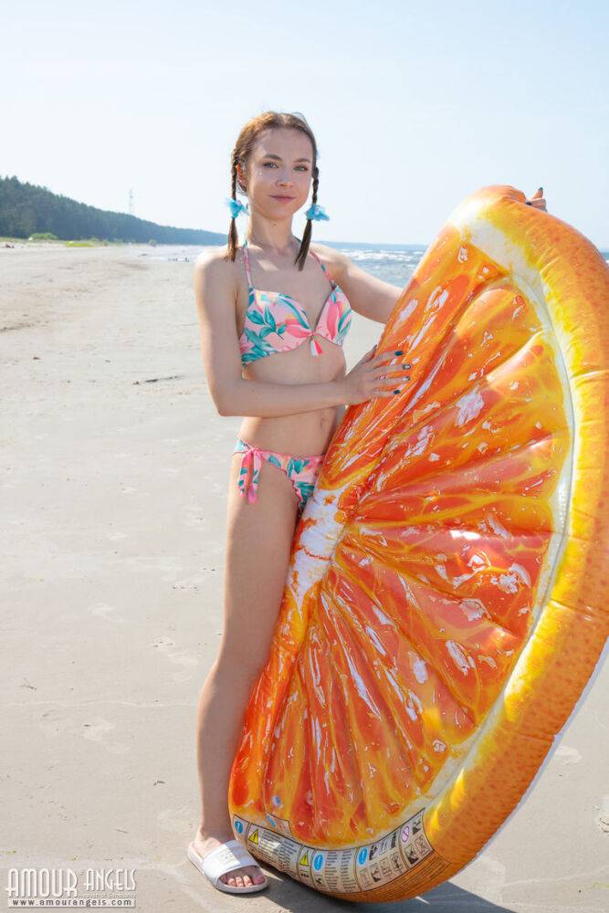 Young girl Nesti doffs a bikini to pose nude in braided pigtails on a beach - #13