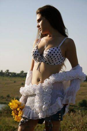 Young brunette Ira I holds sunflowers while stripping totally naked in a field on pornstar6.com