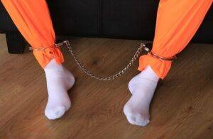 Female prisoner is left alone while cuffed in an orange jumper and white socks on pornstar6.com