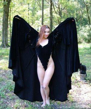 Redhead amateur Amber Lily models nude in a forest draped in a black cape on pornstar6.com