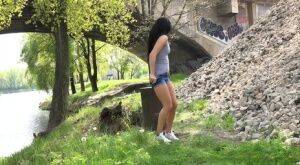 Dark haired traveler Lexi looks for a place to pee and pisses under a bridge on pornstar6.com