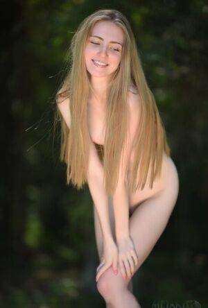 Caucasian teen Lena Flora removes a sexy dress for nude poses on a stump on pornstar6.com