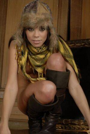 Thin model Corail poses nude in a winter hat plus a scarf and boots on pornstar6.com