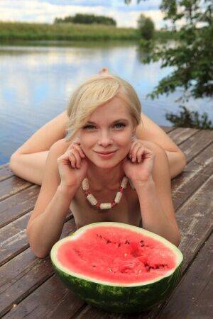 Beautiful blonde Feeona eats a watermelon while posing naked on lakeside dock on pornstar6.com