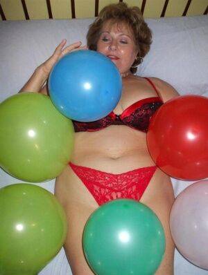 Older lady Busty Bliss plays with balloons before uncupping her natural tits on pornstar6.com