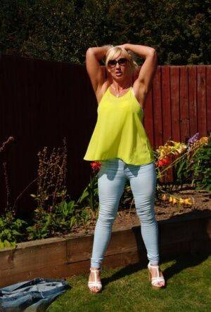 Middle-aged blonde Melody models in a bra and faded jeans in a backyard on pornstar6.com