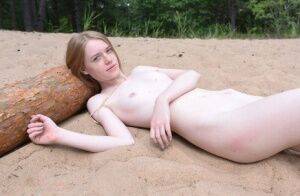 Skinny redhead Gerda models totally naked on a patch of sand in the woods on pornstar6.com