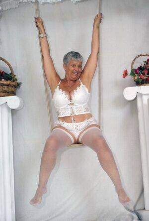 Short haired oma Savana models all white lingerie and hosiery on a swing on pornstar6.com