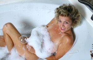 Mature lady soaks in a bathtub while toying her hairy pussy on pornstar6.com