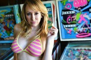 Brett Rossi fingers her pussy in striped OTK socks atop pinball machine on pornstar6.com