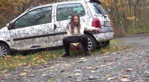 White girl Nicolette Noir takes a piss beside a parked car in a wooded setting on pornstar6.com