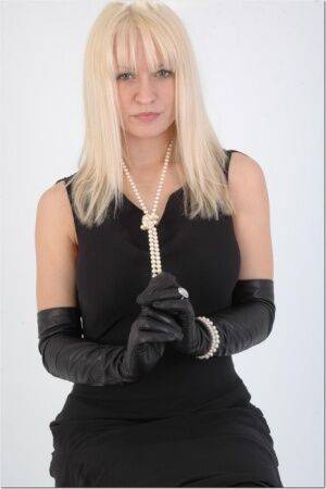 Natural blonde exposes some thigh while wearing long leather gloves on pornstar6.com